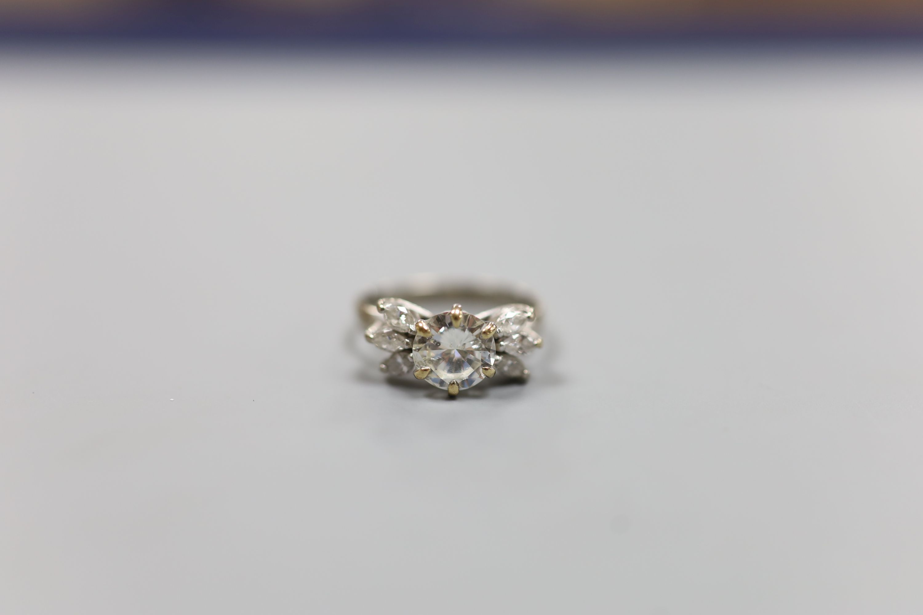 A white metal (stamped 18ct Plat) and single stone diamond ring, with six stone marquise cut diamond set shoulders, size K